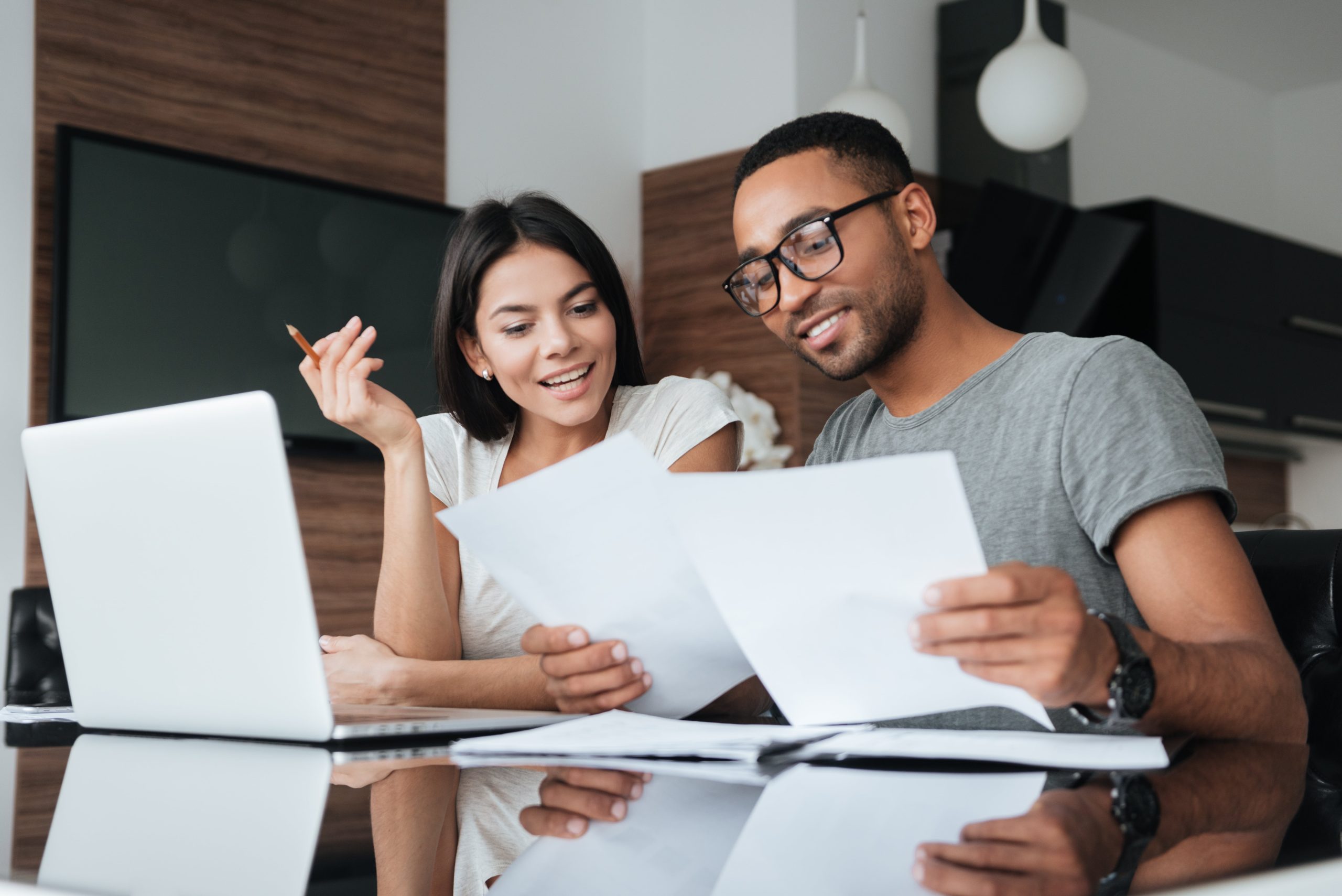 Man and woman sorting through their finances in front of a laptop