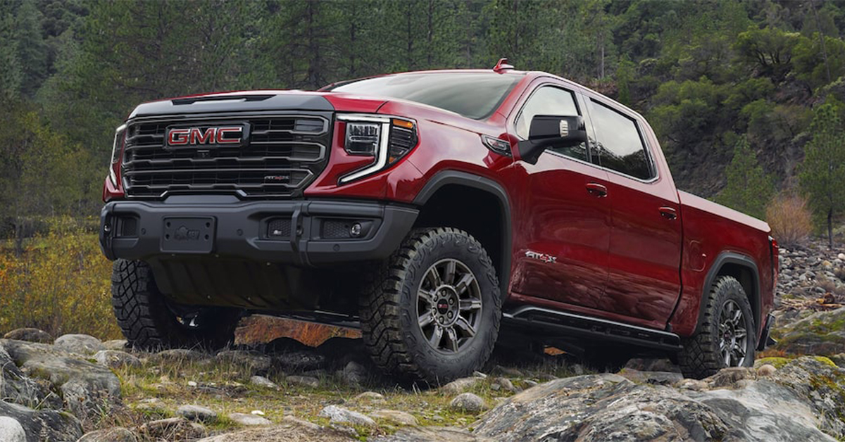 2025 GMC Sierra 1500 AT4 climbing over rocks on a grassy hill